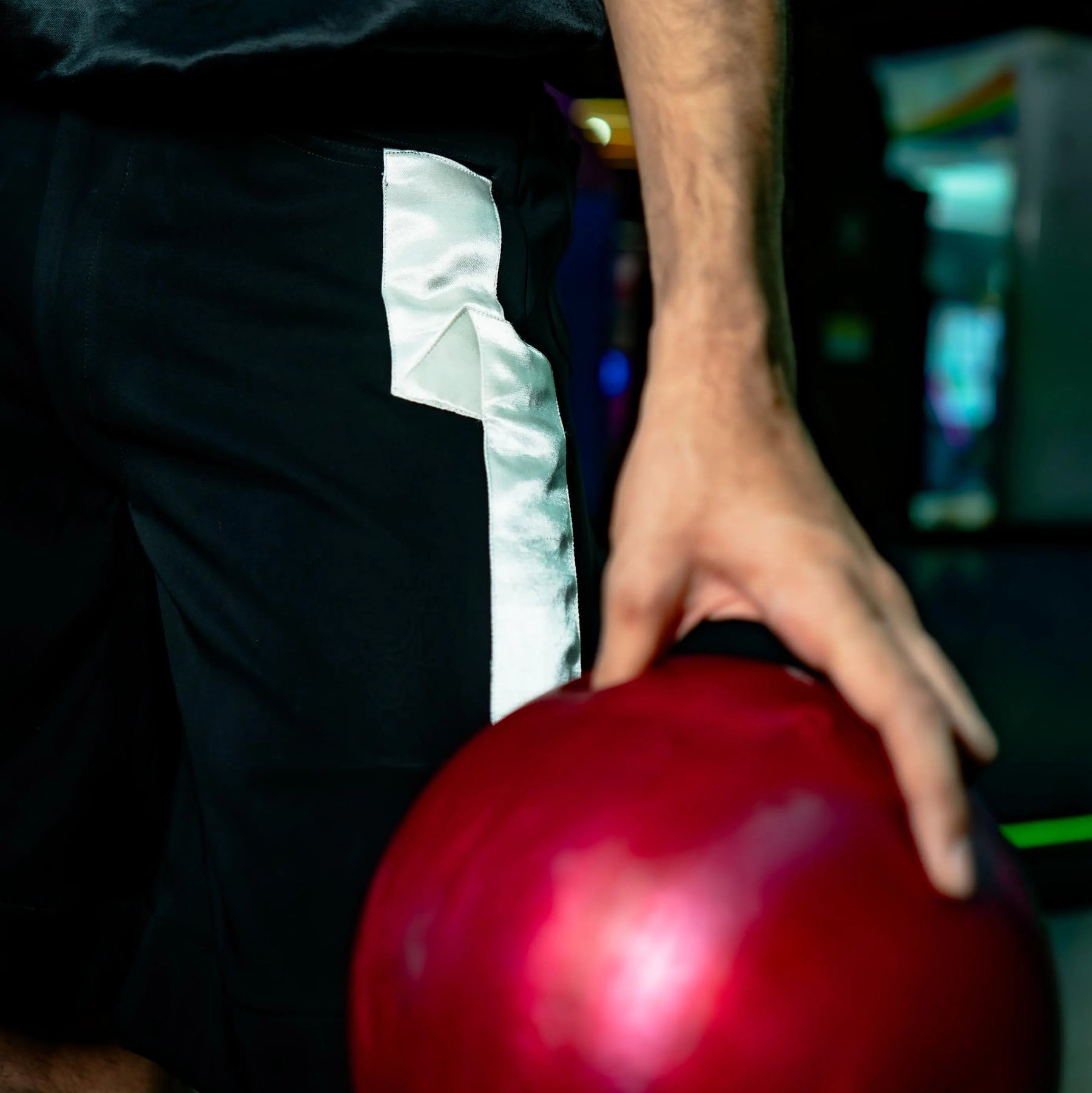 Person holding a red bowling ball in a dark setting